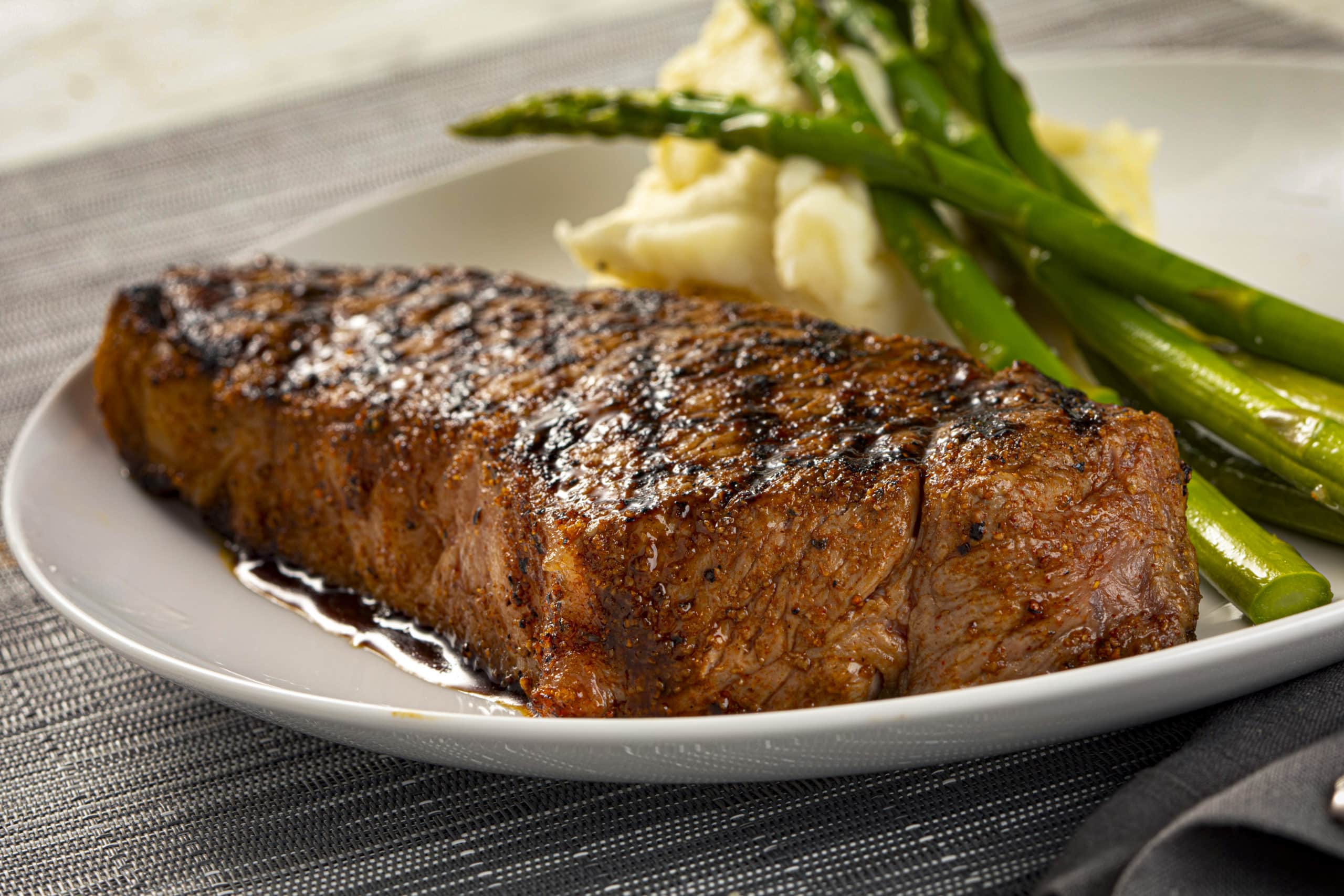 Brio's New York strip steak with mashed potatoes and asparagus on a plate